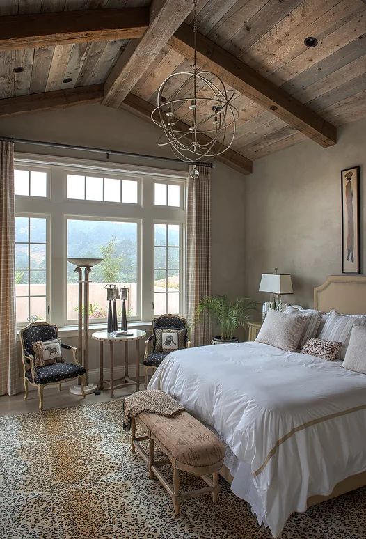 a bedroom with a large bed sitting under a chandelier next to a window