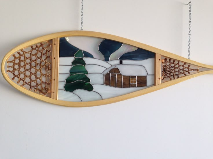 a decorative piece hanging on the wall with a house and tree in it's center