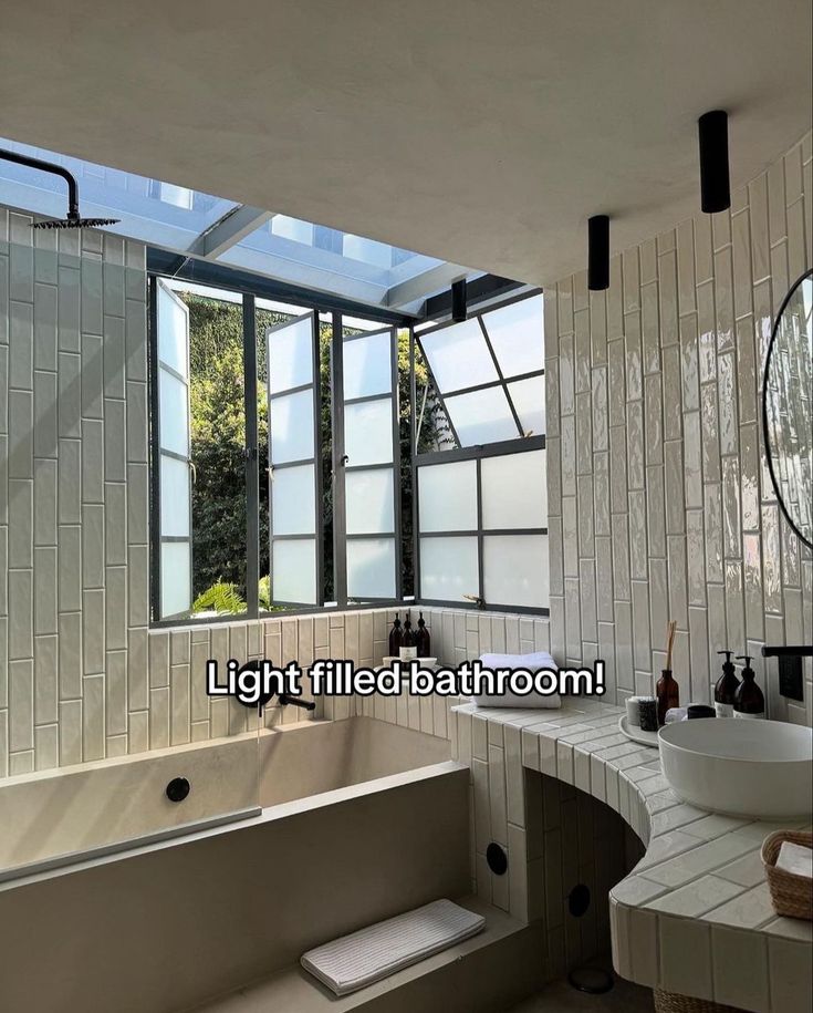 a bath room with a large tub and a sink under a window next to a mirror