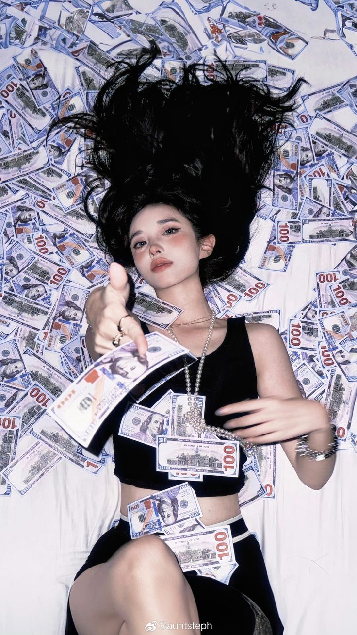 a woman laying on top of a bed covered in lots of money with her hair flying through the air