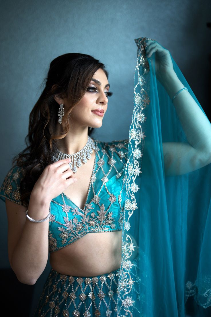 Elevate your beauty with the Magnolias ensemble. Embrace your inner fashionista in this stunning teal Priyanka lehenga adorned with exquisite embroidery and sequins, sure to catch every eye. Pristine elegance meets craftsmanship. A celebration of color and design, the Magnolias ensemble inspires the artist in you. The intricate embroidery and glimmering sequins set you apart, elevating your sense of style with each step. Colour- Teal Fabric & Work Style -- Blouse: Silk with work.- Dupatta: Net d Elegant Turquoise Set With Dupatta, Turquoise Sharara For Wedding, Elegant Turquoise Festive Set, Elegant Turquoise Wedding Sets, Elegant Turquoise Dupatta With Zari Work, Bollywood Turquoise Dresses With Dupatta, Turquoise Bollywood Dress With Dupatta, Party Turquoise Dupatta With Resham Embroidery, Elegant Turquoise Dupatta For Festive Occasions