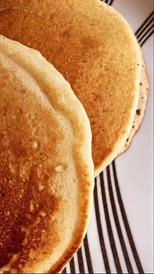 two pancakes sitting on top of a black and white plate next to another pancake