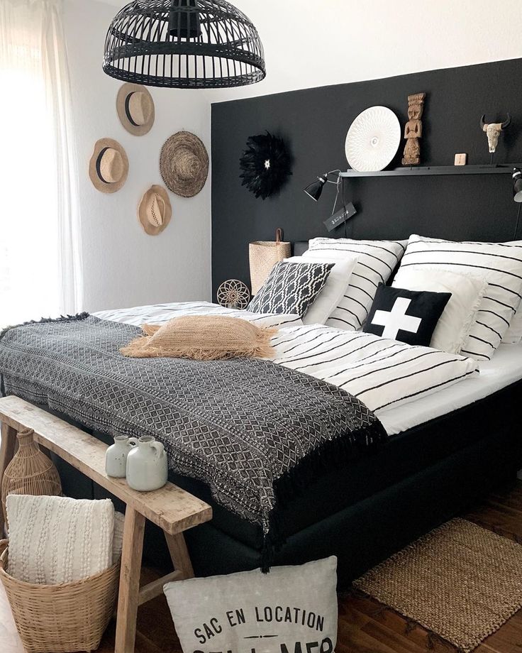 a bedroom with black and white bedding, wicker baskets on the headboard