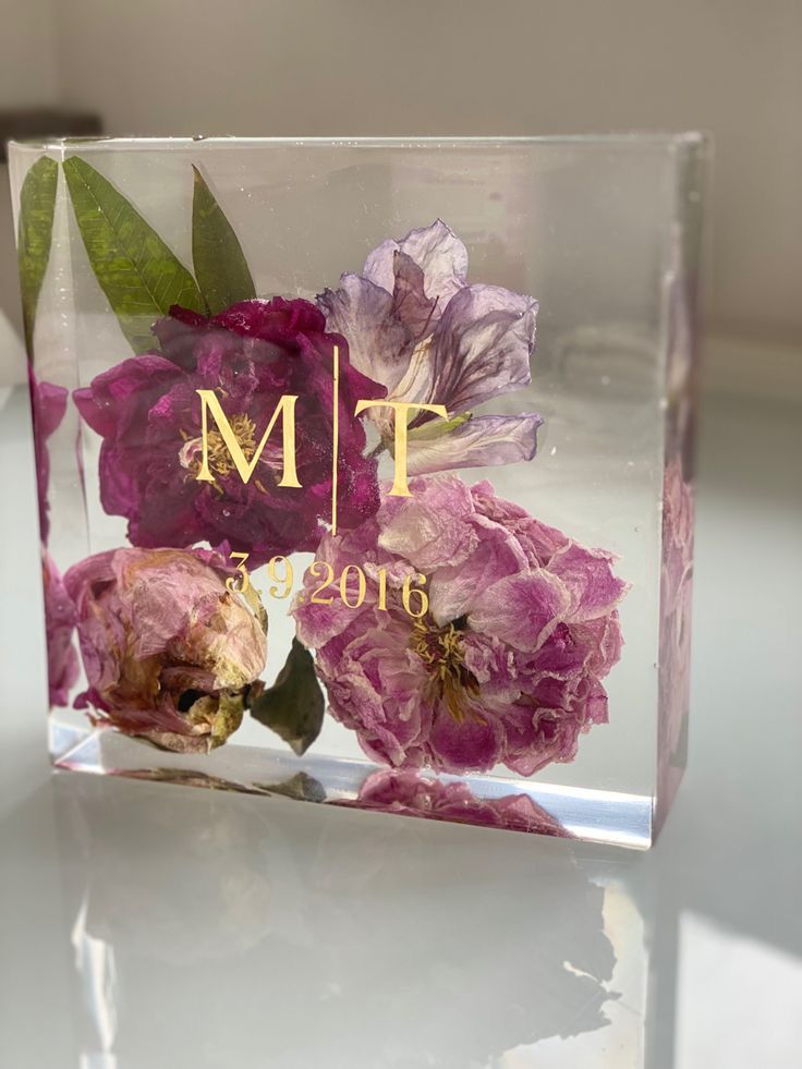 a clear acrylic block with pink flowers on it and the word m t written in gold