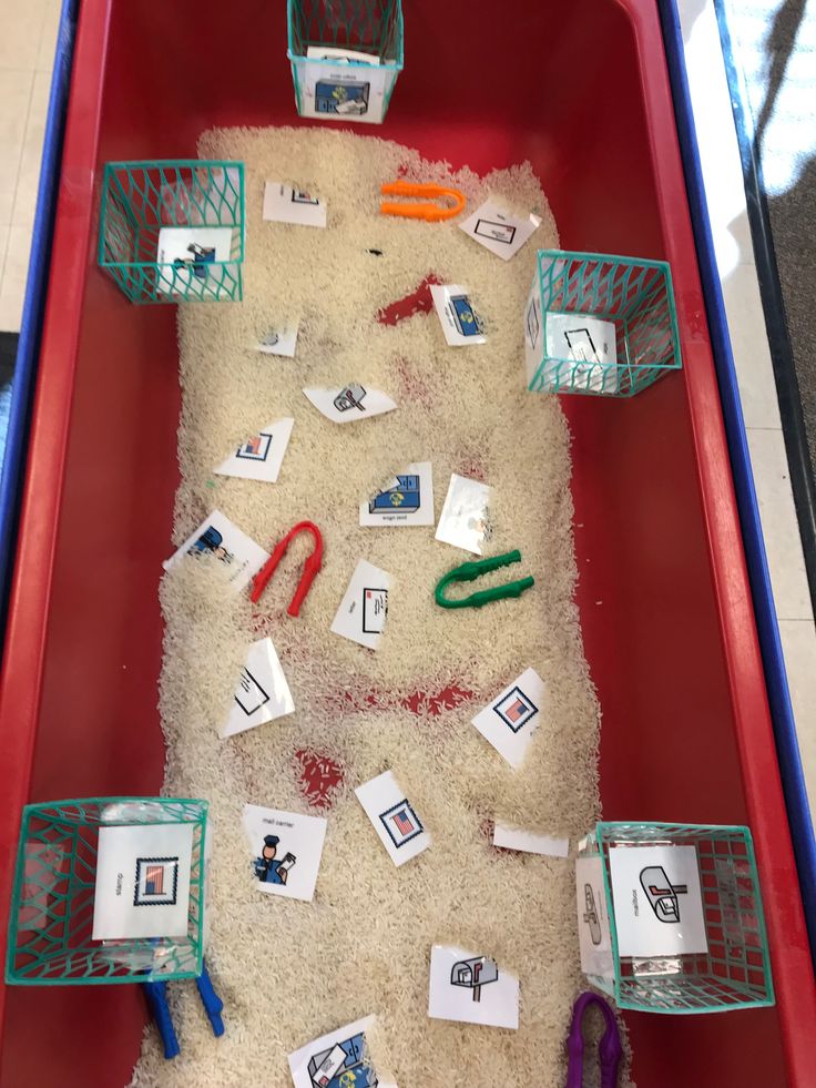 a red bin filled with lots of sand covered in different types of items and scissors