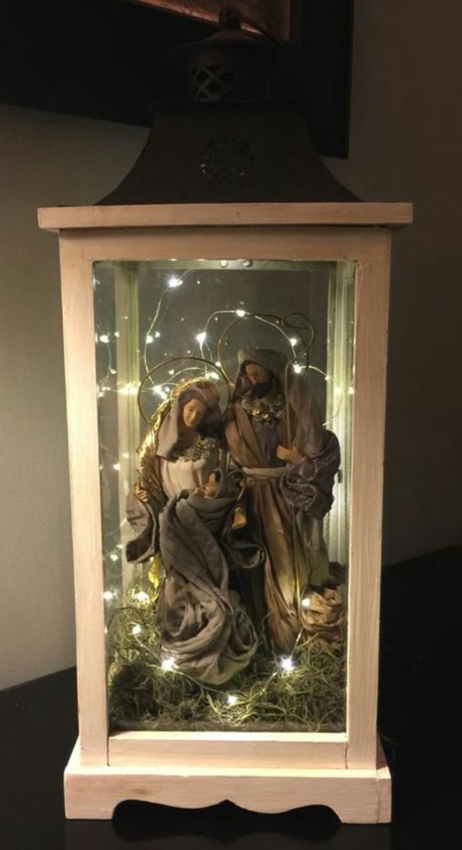 an illuminated nativity scene in a wooden frame with lights on the top and bottom