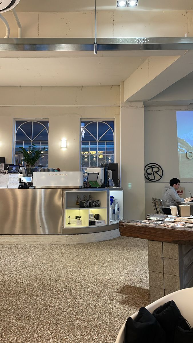 a man is working at a computer in a large room with high ceilings and floor to ceiling windows