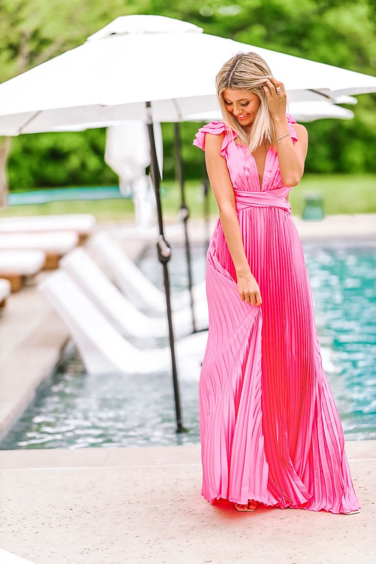 Pleated ruffle maxi gown that is the perfect wedding guest dress! We love the detailing of this dress and that it is a designer dupe for far less! The satin finish fabric is even more stunning in person. Fit: True to size, model is 5'6 wearing size small. There is hidden elastic in the back making it an easy fit. Pink Bridesmaid Maxi Dress With Pleated Bodice, Spring Gala Gown With Pleated Bodice, Pink Pleated Bodice Maxi Dress For Prom, Summer Flowy Gown For Wedding Guest, Ruffled Floor-length Maxi Dress For Gala, Flowy Summer Gown For Wedding Guest, Pink Gown With Pleated Bodice For Spring, Pleated Gown For Wedding And Prom Season, Spring Evening Dress With Pleated Bodice, Floor-length