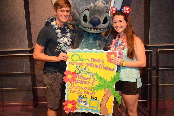 two people standing next to each other with a sign in front of them that says disney