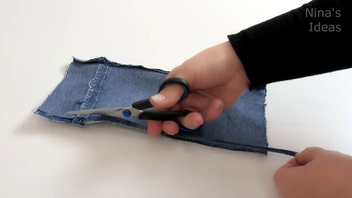 someone cutting up some blue jeans with scissors