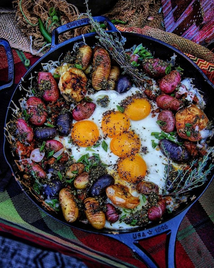 an iron skillet filled with eggs, potatoes and other vegetables on top of a table