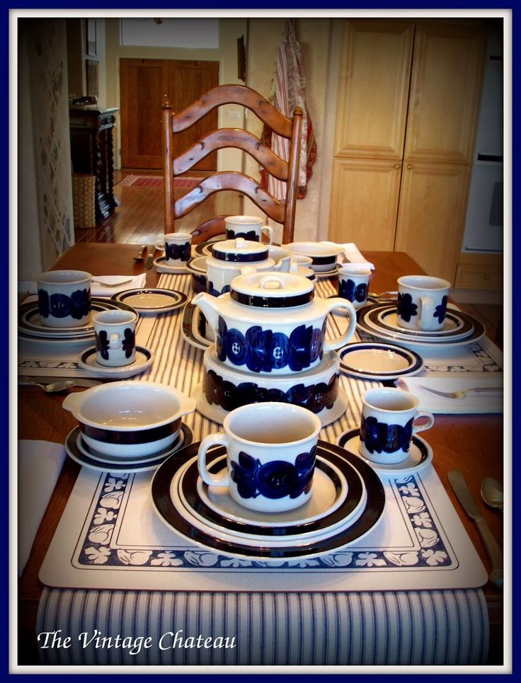 a dining room table set with blue and white dishes on the placemat, china cups and saucers