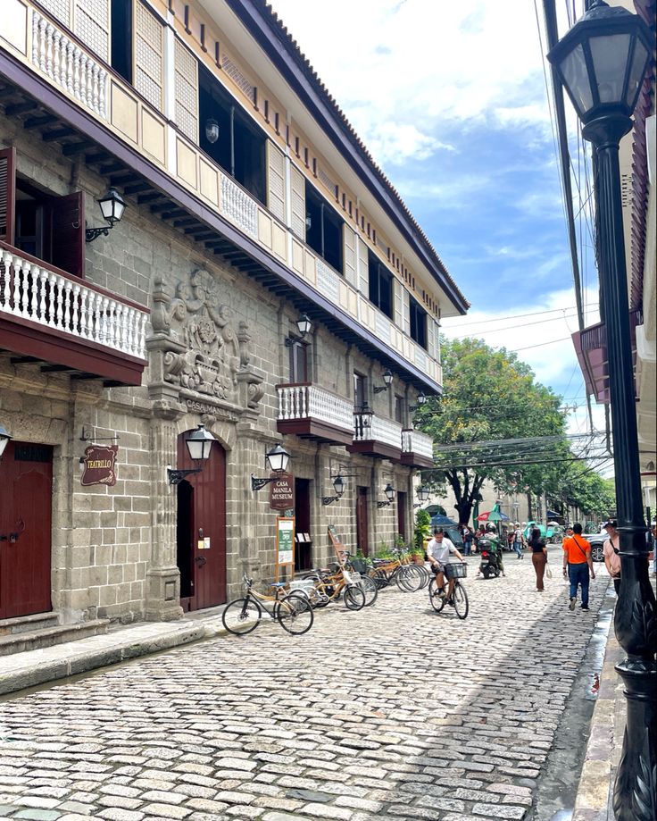 people walking and riding bikes on a cobblestone street