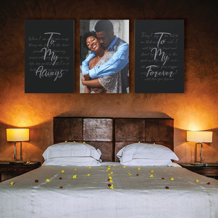 a bed with two pictures hanging on the wall next to each other and flowers in front of it