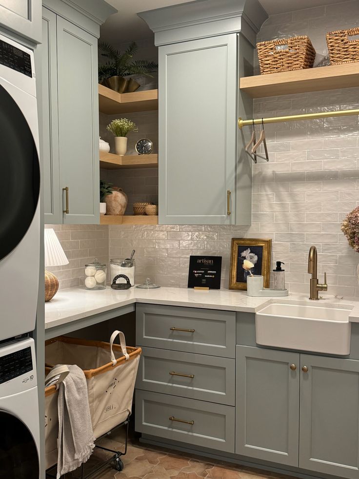 a kitchen with gray cabinets and white counter tops, including a washer and dryer