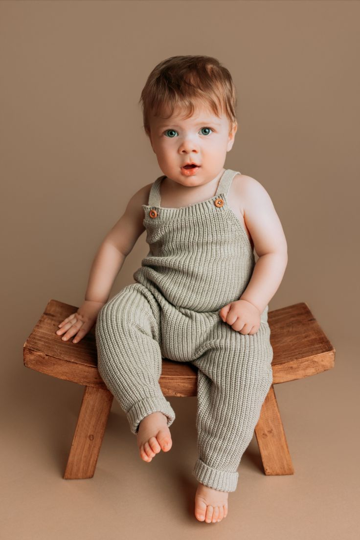 a baby sitting on top of a wooden bench