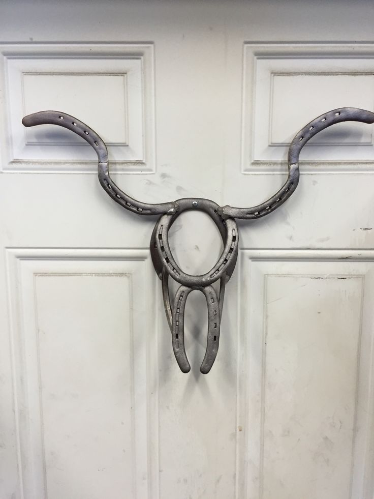 a pair of scissors hanging from the side of a door with horns attached to it