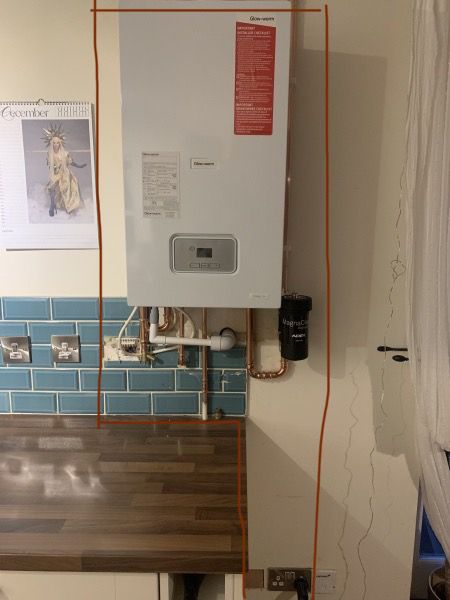 a white tank mounted to the side of a wall next to a wooden counter top