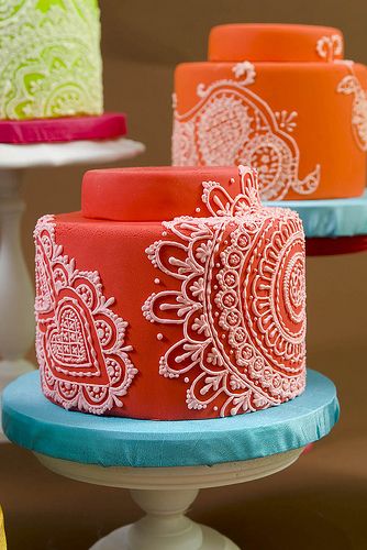 there are three cakes with different designs on the cake stand and one is red, green, orange and white