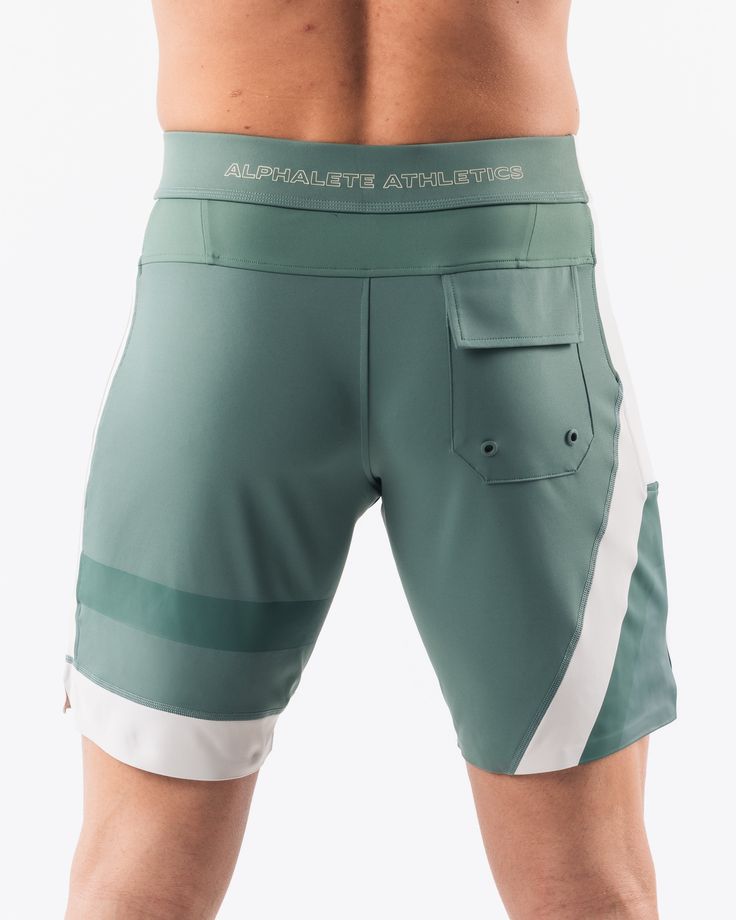 HIGHLIGHTS.. Unlined boardshort. 9” inseam Reflective branding at leg opening and back waistband Elastic waistband with adjustable self-tie drawcords Color-blocking panelling Water resistant fabric FIT SUGGESTION. This item runs true to Alphalete’s standard sizing.. Fit is based off of waist size in inches.. If you are between sizes, we recommend sizing up for a relaxed fit.. Eric is 6’2”/188cm, wearing a size 32. MATERIALS AND WASHING DIRECTIONS. 67% Nylon, 23% spandex. Due to the high saturati Sporty Green Surfing Shorts, Green Sporty Surfing Shorts, Sporty White Shorts For Water Sports, Green Short Bottoms For Water Sports, Green Nylon Swim Trunks For Water Sports, Green Moisture-wicking Bottoms For Water Sports, Green Nylon Shorts For Water Sports, Sporty Nylon Swim Trunks For Surfing, Fitted Swim Trunks With Pockets For Sports