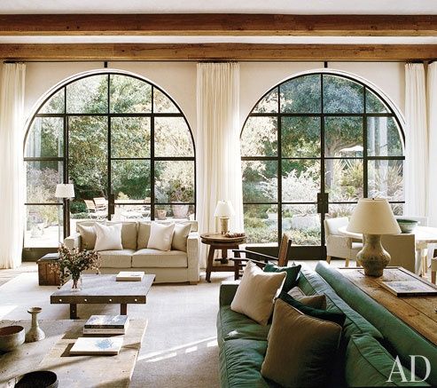 a living room filled with lots of furniture and large arched windows above the couches