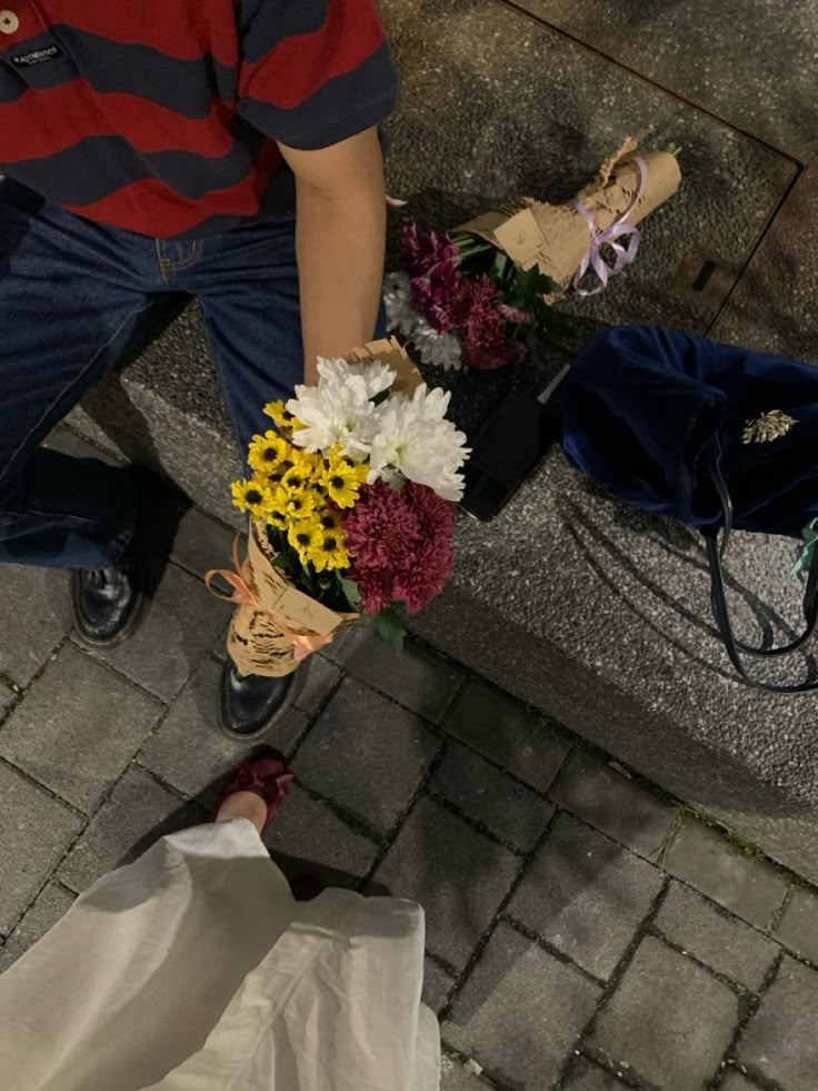 a man is holding flowers on the sidewalk