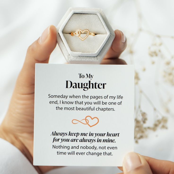 a person holding up a card with a ring on it that says to my daughter