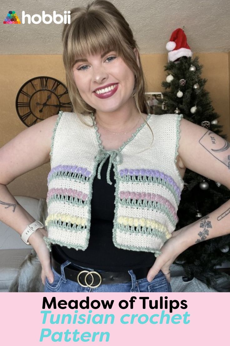 a woman with her hands on her hips wearing a knitted vest and smiling at the camera