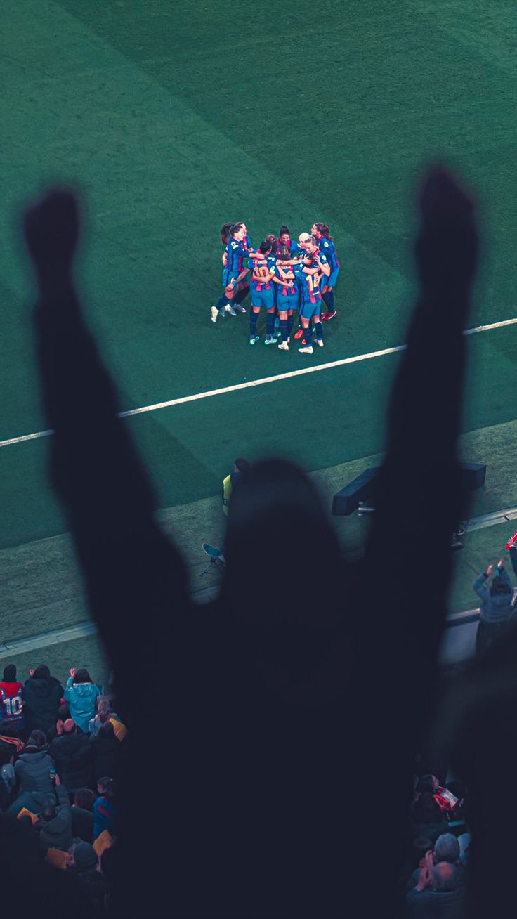 a group of people standing on top of a soccer field with their hands in the air