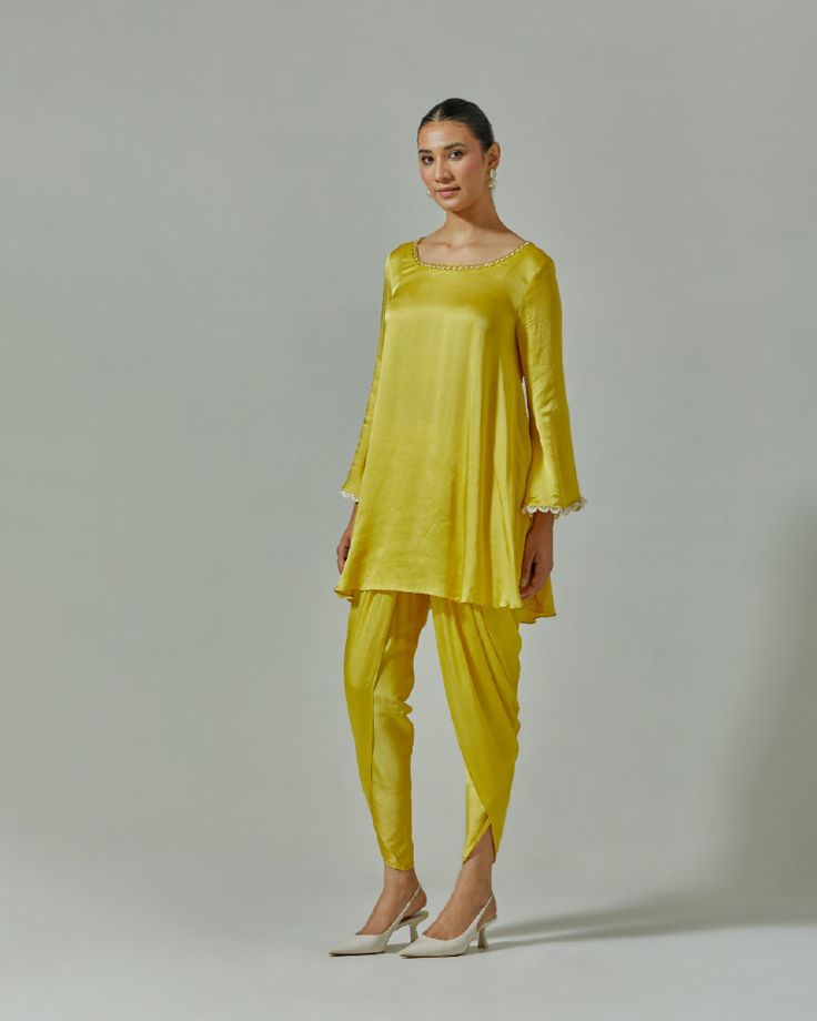 Our Misted Yellow suit set is presented in a soothing shade of yellow. This festive garment was handcrafted from soft modal satin. Delicate cutdana, beaded and zari work at the yoke and cuffs enhance its appeal. It is paired with a tonal embroidered net dupatta to enhance its appeal. For a more dramatic look, choose a pair of dhoti pants to go with the set Color : Yellow Fabric : Modal satin and meshCare : Dry clean onlyFit : Flared The model wears size S. Yellow Suit, Dhoti Pants, Zari Work, Net Dupatta, Dramatic Look, Yellow Fabric, Pakistani Outfits, Suit Set, Shades Of Yellow