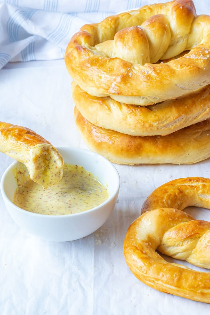 a stack of pretzels sitting next to a small bowl of dip and bread