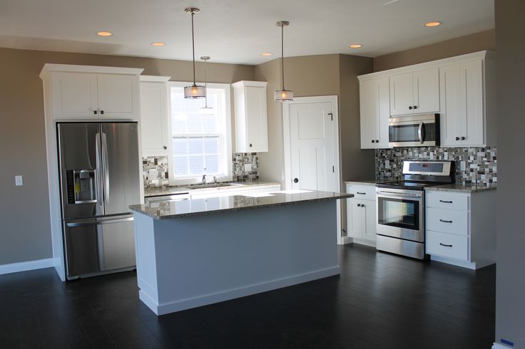 an empty kitchen with white cabinets and stainless steel appliances in the middle of the room