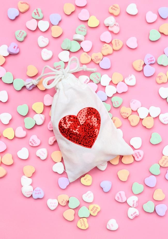 a small bag filled with hearts on top of a pink table covered in confetti