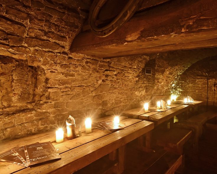 candles are lit on the long table in an old stone room with exposed brick walls