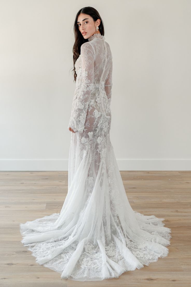 the back of a woman wearing a white wedding dress with sheer lace and long sleeves