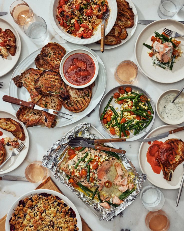 a table topped with lots of plates and bowls filled with different types of food on top of it