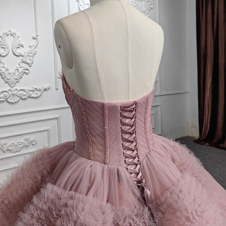 a pink dress with ruffled layers is displayed on a mannequin headdress