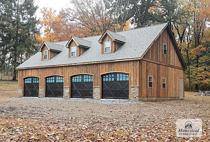 a three car garage with two windows on the front and one door open, surrounded by leaves