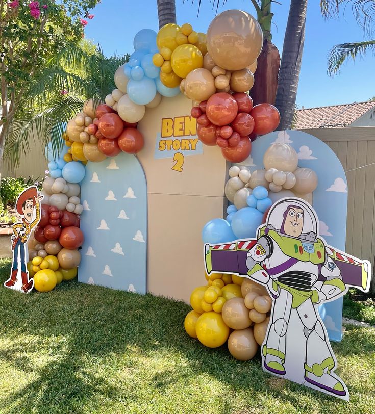 balloon arch with buzz lightyear and woody the spaceman on it for an outdoor birthday party