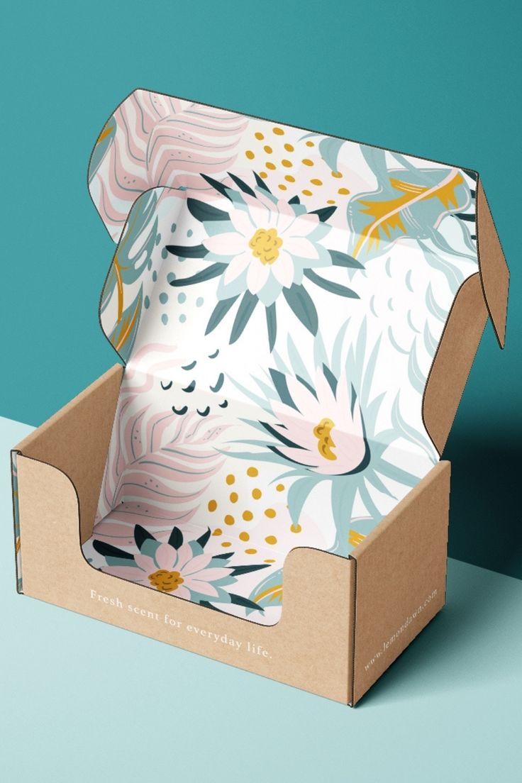 an open cardboard box with floral designs on the lid and inside, sitting on a blue surface