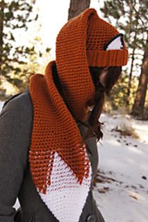 a woman wearing an orange and white knitted scarf with a fox head on it