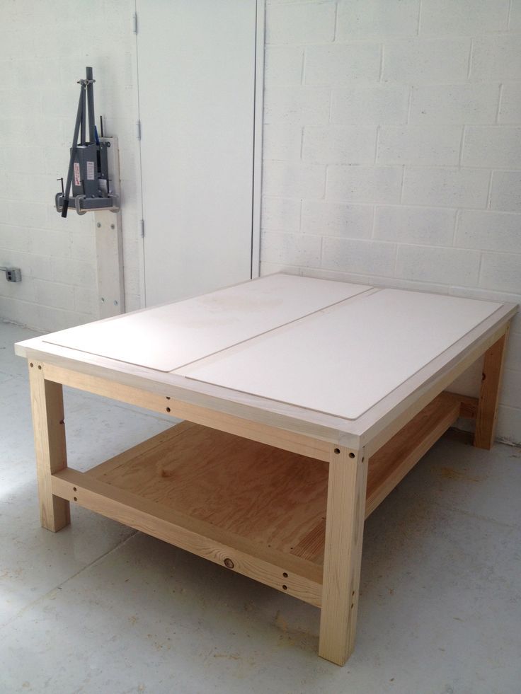 an unfinished coffee table sitting on top of a hard wood floor next to a white brick wall