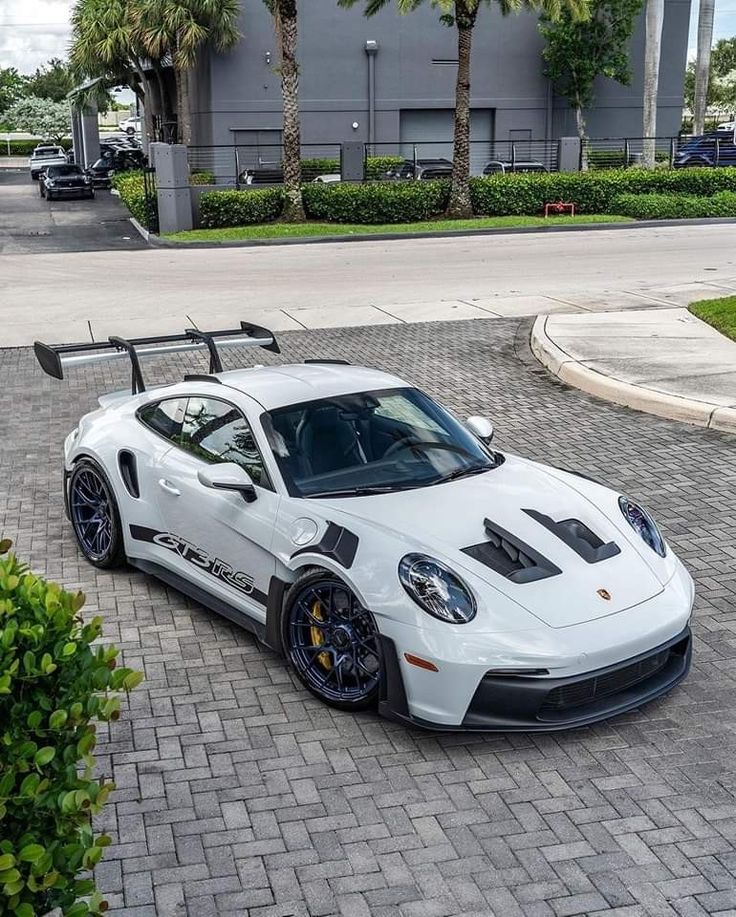 a white sports car parked in front of a building with palm trees on the side