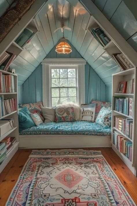 an attic bedroom with bookshelves and a window seat in the corner, filled with books