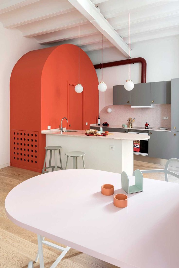 a kitchen with an orange wall and white counter tops in the center of the room