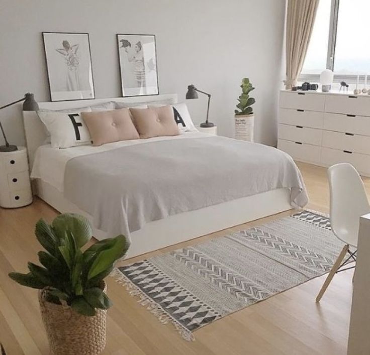 a bedroom with white walls and wooden flooring has a large bed in the center