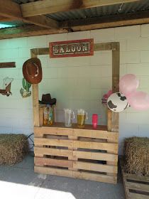 a bar made out of wooden pallets with balloons and decorations on the wall behind it