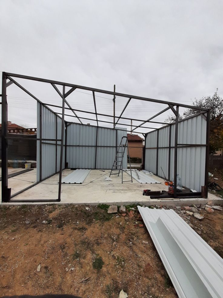 an unfinished building with metal framing in the foreground and other construction materials on the ground