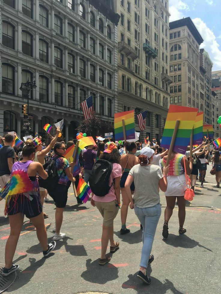 a group of people walking down a street holding rainbow flags