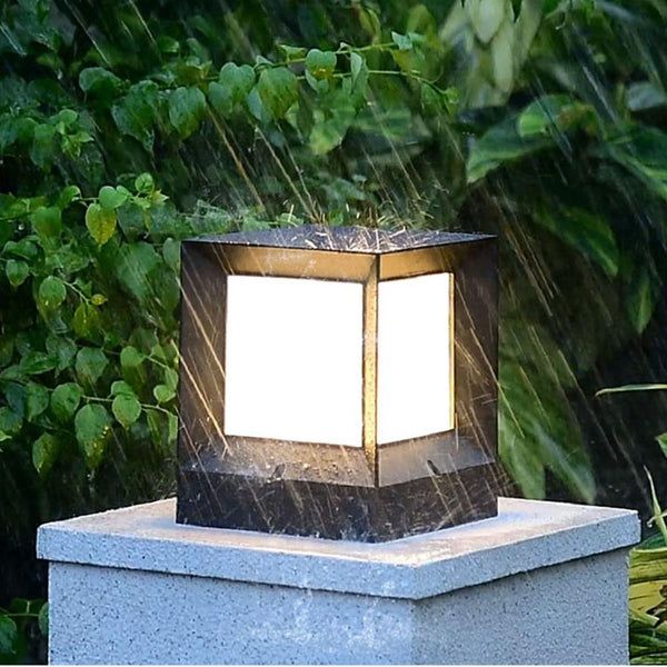 a lamp that is sitting on top of a cement block in the rain with green plants behind it